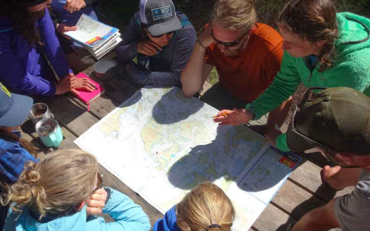 a group of students study a map on outward bound mountaineering course